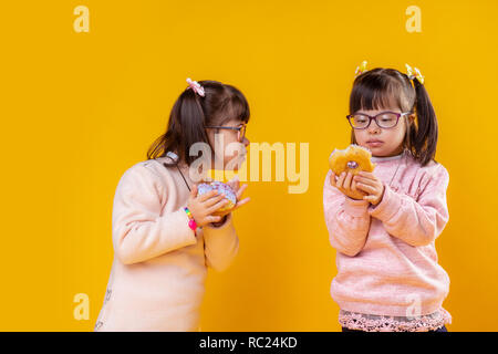 Kleine Mädchen mit Down-syndrom ihre Donuts beobachten Interessiert Stockfoto