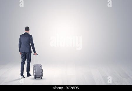 Junge Unternehmer in einem weißen grenzenlosen Raum gehen Mit zurück und Gepäck auf seiner Hand Stockfoto