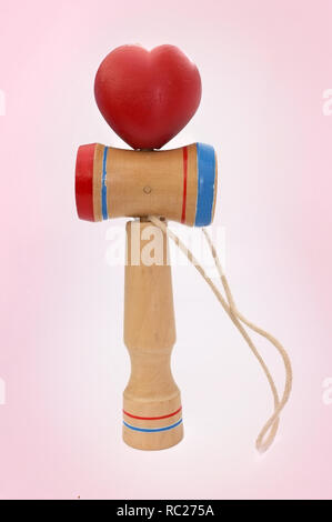 Kendama, einem traditionellen japanischen Spielzeug bestehend aus einem Schwert und einer Kugel durch einen String in Herzform gerollt, auf rosa Hintergrund isoliert verbunden ist, anhand von quantitativen Simulatio Stockfoto