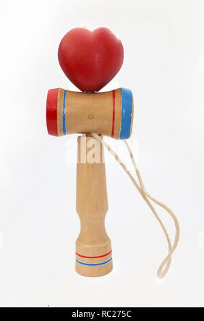 Kendama, einem traditionellen japanischen Spielzeug bestehend aus einem Schwert und einer Kugel durch einen String in Herzform gerollt, auf weißem Hintergrund verbunden, Konze Stockfoto