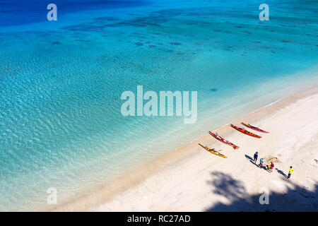 Kajaks und Personen, die in einem tropischen Strand mit türkisblauen Wasser im idyllischen Insel Flachkopfkatze, Japan. Stockfoto