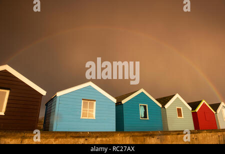 Regenbogen über Holzhütten am Southwold in Suffolk, England Großbritannien Stockfoto