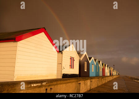 Regenbogen über Holzhütten am Southwold in Suffolk, England Großbritannien Stockfoto