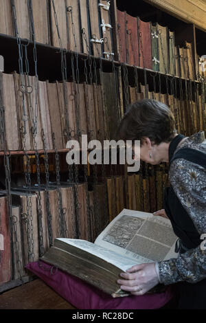 Dr. Rosemary Firman inspiziert, Foxe's Buch der Märtyrer während der jährliche Reinigung der Hereford verkettete Bibliothek bei Hereford Cathedral, Herefordshire. Die Verkettung der Bücher war die am weitesten verbreitete und effektive Sicherheit System in den europäischen Bibliotheken vom Mittelalter bis in das 18. Jahrhundert, und Hereford Cathedral aus dem 17. Jahrhundert verkettete Bibliothek ist die größte mit all seinen Ketten, Stangen, um zu überleben und Schlösser intakt. Stockfoto