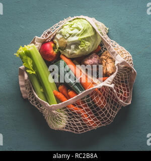 Verschiedene Bauernhof Bio Gemüse aus dem lokalen Markt in Net string wiederverwendbare Tasche auf rustikalen Hintergrund, Ansicht von oben. Saubere und gesunde Lebensmittel Konzept. Stockfoto