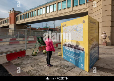 Frau auf der Suche nach Plänen für die Metrolink Trafford Park Line Bau in der Nähe der Intu Trafford Centre Stockfoto