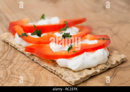 Ein Roggen Brot Cracker mit Fett frei Haus und geschnittene rote Paprika, garniert mit Petersilie. Auf einem Schneidebrett Olivenholz. England UK GB Stockfoto