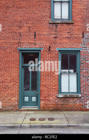 Ein altes Holz Rahmen von Tür und Fenster grün lackiert gegen eine verwitterte Red brick wall in der kleinen Stadt Elizabeth City, North Carolina. Stockfoto