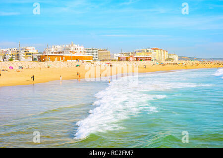 COSTA DA CAPARICA, Lissabon, Portugal - 17. SEPTEMBER 2018: die Menschen in der Stadt am Strand in der Abendsonne, City Skyline, Promenade mit Cafés und Restaurants. Stockfoto