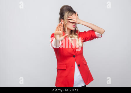 Stop, ich möchte nicht das zu sehen. Porträt der schönen Business Lady mit Frisur und Make-up in Rot fancy Blazer, stehend für ihre Augen mit Stop Stockfoto