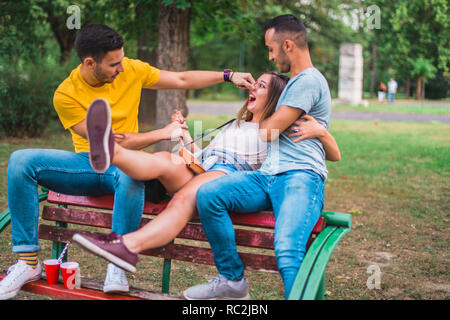 Kaukasische Freunde sitzen auf einer Bank im Park, Witze und Spaß haben Stockfoto