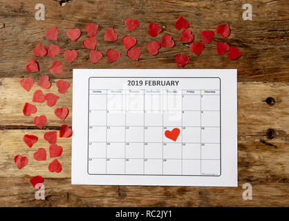 Konzeptionelle Bild von 2019 Februar Kalender und Gegenwart Geschenk mit roter Schleife auf rustikalen vintage Tabelle in sich bereit für Saint Valentines Tag gewickelt Stockfoto