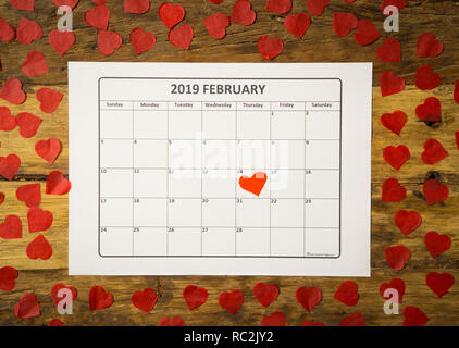 Konzeptionelle Bild von 2019 Februar Kalender und Gegenwart Geschenk mit roter Schleife auf rustikalen vintage Tabelle in sich bereit für Saint Valentines Tag gewickelt Stockfoto