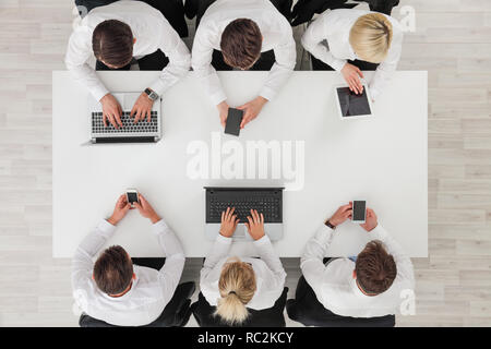 Blick von oben auf die verschiedensten Menschen von Business Team Gruppe über Smartphone, Handy, Tablet-PC und Computer laptop zu treffen Stockfoto