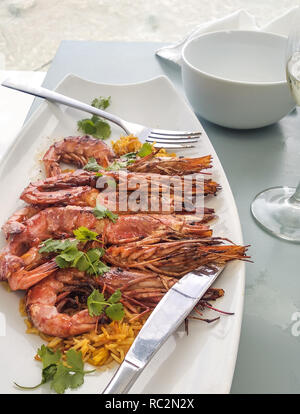 Gegrillte Garnelen in weißen Teller mit Messer und Gabel in der Nähe bis in Restaurant Stockfoto