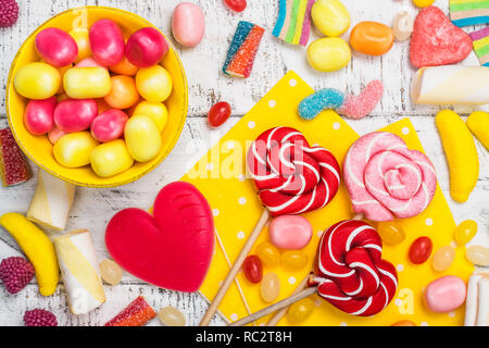 Rosa Bonbons, Lutscher und Jelly Beans auf weißem Holz- Hintergrund. Süße Grußkarte. Kopieren Sie Platz. Ansicht von oben Stockfoto