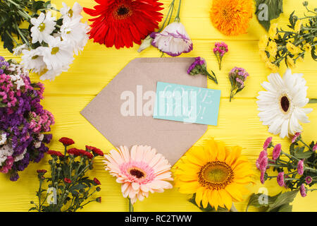 Ich liebe sie und viele verschiedene Arten von Blumen auf Holz. Ansicht von oben. Gelbe Holzschreibtisch Hintergrund. Stockfoto