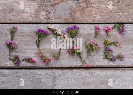 Liebe Wort aus statice limonium Blumen. Ansicht von oben. Alte vintage Schreibtisch aus Holz Oberfläche Hintergrund. Stockfoto