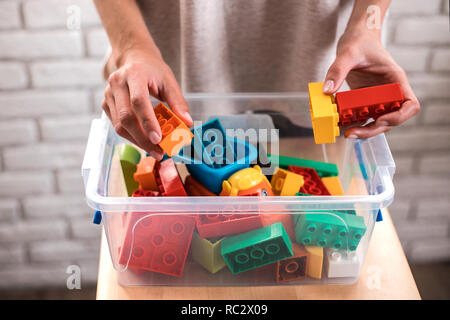 Die Frau Hände setzen farbige Bausteine in Box. Stockfoto