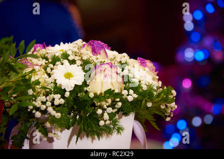 Ein Blumenstrauß in einer Box auf dem Hintergrund der hellen bunten Bokeh. Stockfoto