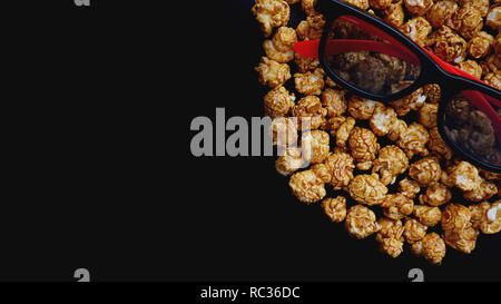 Abstraktes Bild von Viewer, 3D-Brillen und Popcorn auf schwarzem Hintergrund Stockfoto