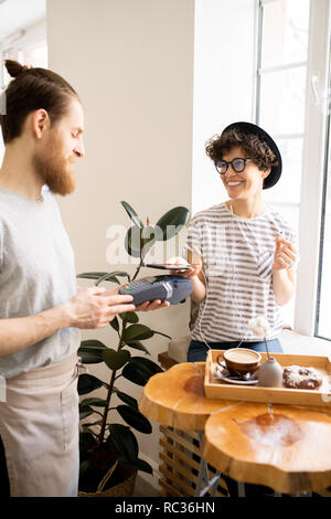 Bezahlen mit Gadgets im Coffee Shop Stockfoto