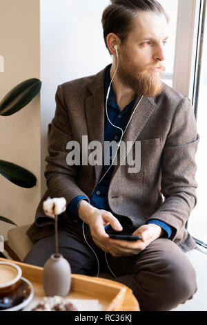 Die introspektive hipster Mann hören die Musik im Kopfhörer. Stockfoto