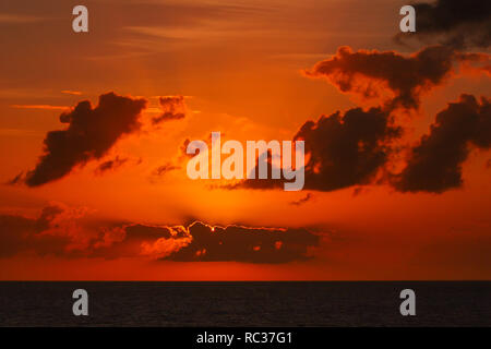 Blick auf die malerische Seenlandschaft Sonnenuntergang mit Wolken über die untergehende Sonne. Sonnenstrahlen, die durch die Wolken. Stockfoto