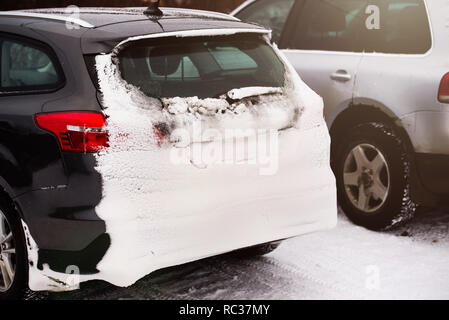 Die Rückseite des Autos ist mit Schnee bedeckt. Schneefall. Close-up. Auto Anmeldung Zeichen ist nicht sichtbar wegen Schnee Stockfoto