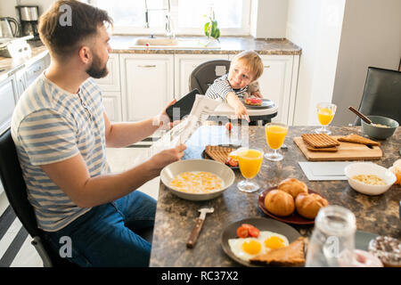 Junger Vater beim Frühstück Stockfoto