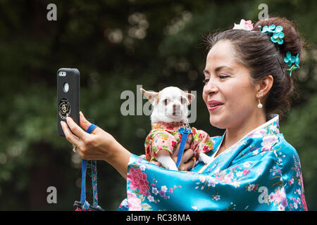 Eine Frau trägt einen Kimono nimmt eine selfie, als sie ihren kleinen Hund hält, in einem Kimono Kostüm gekleidet, bei Doggy Con in Atlanta, GA, am 18. August 2018. Stockfoto