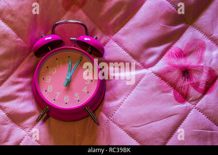 Rosa girly vintage Wecker auf eine rosa Decke Hintergrund isoliert Stockfoto