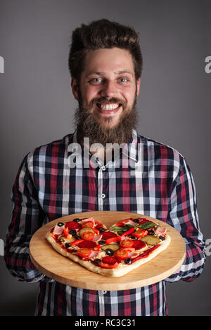 Glücklich lächelnde Mann, hausgemachte Pizza in Herzform Stockfoto