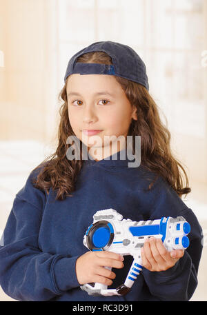 Glückliche kleine Mädchen, dass eine Waffe in der Hand und tragen junge Kleidung Stockfoto