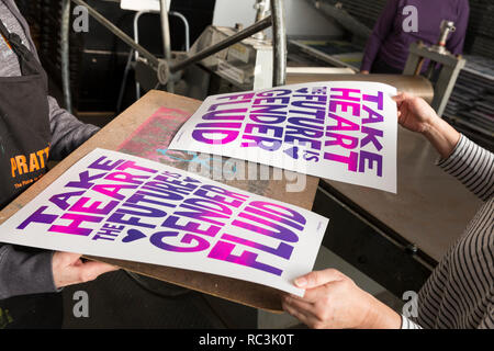 Seattle, Washington, USA. 12. Januar 2019. Freiwillige bewegen Fenster beendet druckt auf trockenständer am Pratt Fine Arts Center Print Studio. Die Anhänger wurden eingeladen, positive Widerstand Plakat ausdrucken bei einer Party für die kommende Womxn im März auf Seattle 2019 erstellen. Die Rallye und März, durch Seattle Womxn marschiert vorwärts organisiert, wird am 19. Januar 2019 statt, Anpfiff ein Wochenende von Gebäude macht durch Gemeinschaft, Protest, und Aktivismus. Credit: Paul Christian Gordon/Alamy leben Nachrichten Stockfoto