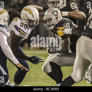 Oakland, Kalifornien, USA. 24. Dezember 2015. San Diego Chargers defensive Ende Ricardo Mathews (90) befasst sich mit der Oakland Raiders zurück laufen Latavius Murray (28) am Sonntag, den 24. Dezember 2015, an O. co Coliseum in Oakland, Kalifornien. Die Räuber besiegt die Ladegeräte 23-20. Credit: Al Golub/ZUMA Draht/Alamy leben Nachrichten Stockfoto