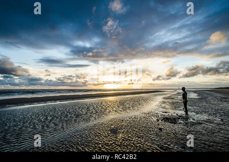 Antony Gormley "einem anderen Ort". Die lebensgroße Gusseisen Figuren / Statuen über Crosby Strand verstreut sind in Merseyside Stockfoto