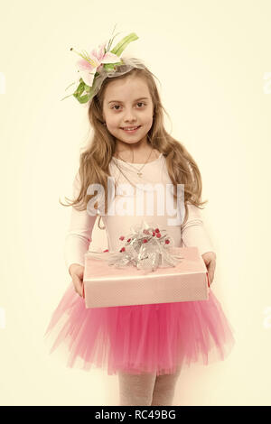 Kind mit Blume im langen blonden Haare isoliert auf Weiss. Mädchen ballerina Lächeln mit Box im rosa Tutu Rock. Vorhanden oder Geschenk geben. Urlaub, Geburtstag, Jubiläum zu feiern. Boxing Day Konzept. Stockfoto