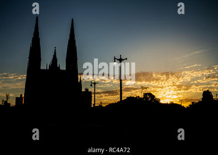 Abbildung gegen das Licht einer riesigen Kathedrale. An seiner Seite den Sonnenuntergang Farbstoffe die Wolken der goldenen Farben. Stockfoto