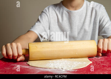 Kid Hände rollen Sie den Teig mit dem Nudelholz auf Silikon Teig rollen und Backen mat Stockfoto