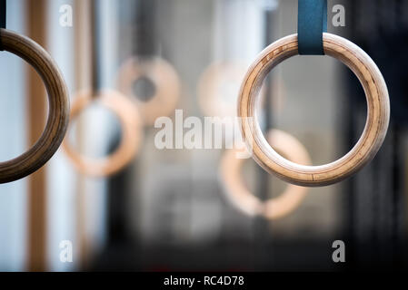 Holz- sport Ringe in der Turnhalle, in der Nähe gesehen - mit selektiven Fokus. Paar Ringe ist unscharf im Hintergrund. Gymnastik Ausstattungskonzept Stockfoto