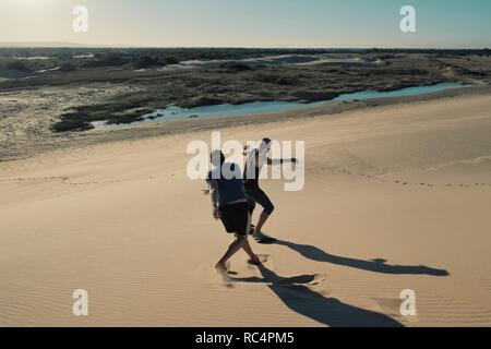 Santa Cruz, Bolivien - Sept. 5 2018: Zwei junge Mann Sandboarden in der Wüste Sand Dünen in der Nähe der Stadt Stockfoto