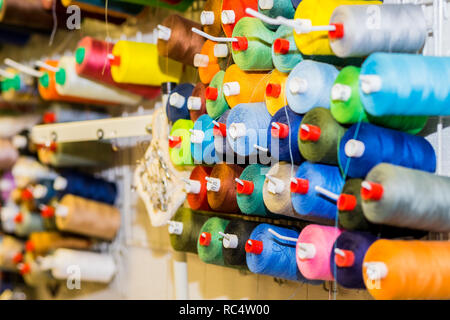 Spulen des bunten Faden nähen Studio. Selektive konzentrieren. Bunte Stickgarn Ventilschieber mit in der Bekleidungsindustrie, Reihe von bunten Garnen Brötchen, Nähgut. Stockfoto