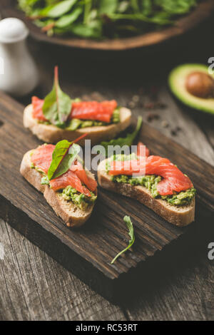 Gesunde Sandwiches mit Avocado und Lachs auf Holz Schneidebrett. Selektiver Fokus, getönten Bild Stockfoto