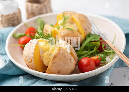 Gefüllte Kartoffeln mit Käse überbacken, Sauerrahm und Dill. Detailansicht, selektiver Fokus Stockfoto