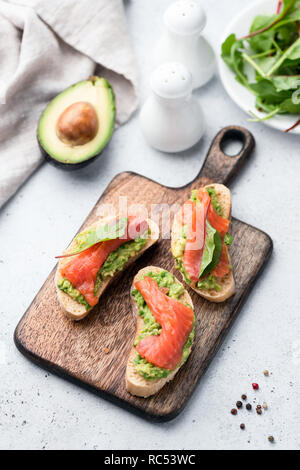 Leckere Sandwiches mit Avocado und Lachs auf Holz Schneidebrett Stockfoto