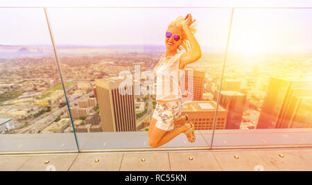 Blonde Frau mit Blick von oben auf die Stadt Los Angeles in Kalifornien, USA. Touristische Überbrückungskabel an die Innenstadt von LA Skyline bei Sonnenuntergang. Reise und Tourismus amerikanische Konzept. Stockfoto