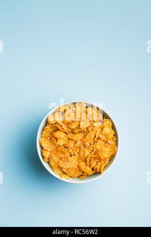 Müsli oder Cornflakes in der Schüssel auf blauem Hintergrund. Ansicht von oben. Stockfoto