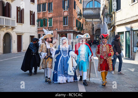 Venedig, Italien - 10. Februar 2018: Männer und eine Frau in Masken und gelben und blauen Kostüme auf der Straße während des Karnevals Stockfoto