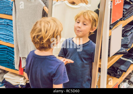 Der Junge versucht auf der Kleidung in der Kleidung der Kinder speichern Stockfoto